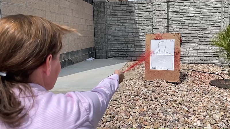 Woman firing AIIRO non-lethal defense gel at a target