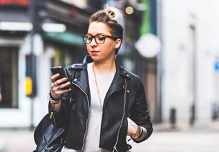 A woman walks down the street looking at her phone