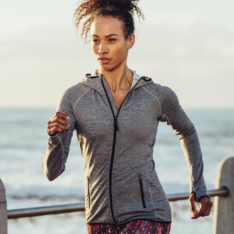 A woman jogs down the beach confidently