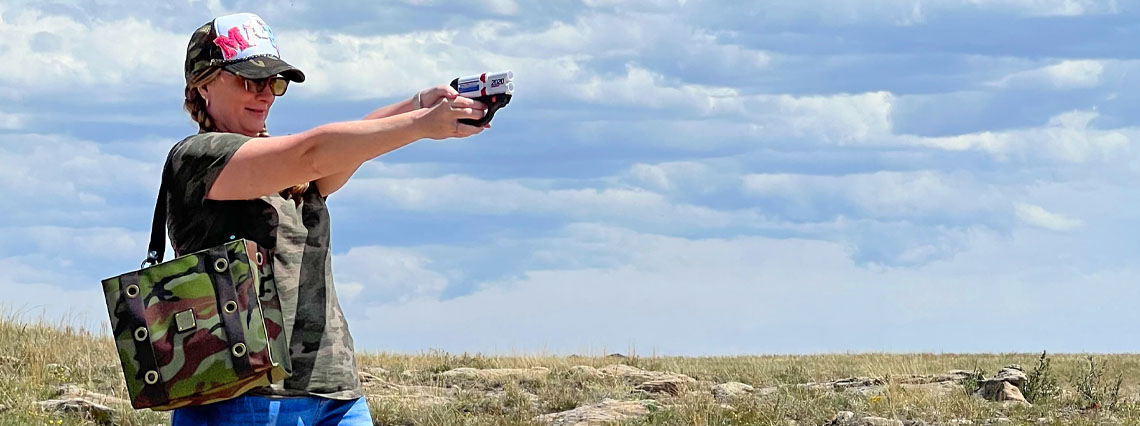 Woman firing HERO 2020 while carrying her MICHE handbag